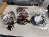 Four plastic bags filled with various test leads and clips on tabletop