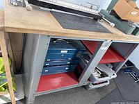 Front view showing wood surface, gray steel frame, red shelves