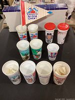 All ten cups displayed upright with FanFest flag inserted in one cup; two cups shown with red snack lids