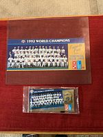 Top view showing larger team photo card and sealed pin/card on red surface