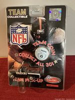 Front view of sealed blister pack showing die-cast Ford F-150 with Raiders graphics and included team coin