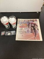 Lot overview showing two glasses, newspaper section, and three bagged pins
