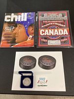 Group shot of all items: silver coin in box, two puck coasters, Chill magazine, Sports Illustrated special issue