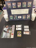 Full lot on table including display board, cups, program, card pack, ticket stubs