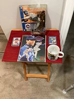 Full lot featuring sealed action figure, mug, magazine, unopened card pack with rookie card, and single Score card on red table