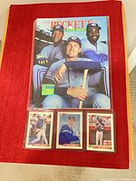 Magazine and three Bowman baseball cards in sleeve on red surface