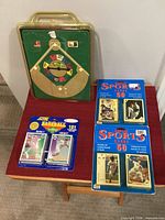 Front view of sealed baseball board game and three sealed trading card blister packs on table