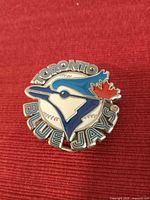 Front view of metallic belt buckle with enamel Toronto Blue Jays logo