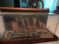 full front view of ship diorama in glass case with POW label