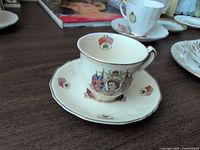Cup on saucer showing portrait, flags and gilt trim
