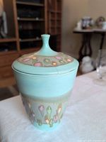 Front view of ceramic jar with lid showing aqua body and decorative drip band
