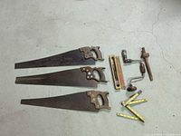 Group shot of three saws, brace drill, auger bit box, two folding rules