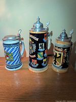 Front view of three ceramic beer steins with lids