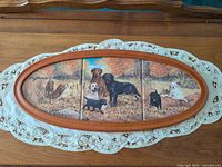 Full view of oval framed three-tile artwork of Labradors