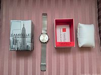 Watch with box and pillow laid out on surface