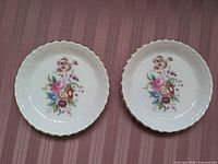 Front view of both Coalport Junetime dessert plates showing floral design and gold-trimmed scalloped edges
