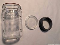 Jar, glass lid insert, and metal screw band side by side on surface