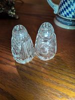 Two crystal diamond-cut shakers standing side by side on wood surface