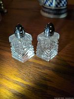 Front view of both crystal shakers showing stepped facets and silver tops