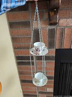 Entire hanging two-tier teacup planter against brick wall