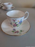 Teacup on saucer showing floral pattern and gold rim
