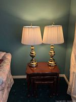 Pair of matching brass-tone table lamps on side table