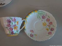Teacup and saucer front showing floral decoration and yellow band