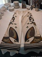 Front view of pants laid flat showing full graphic print and wide legs