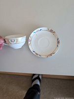 Teacup held beside saucer showcasing pattern and size