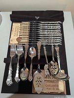 Full set in cloth roll showing knives, forks, spoons, slotted spoon, pie server, warranty card