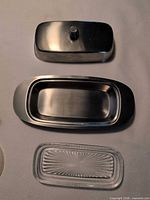 butter dish components separated: stainless lid, stainless base, clear glass insert
