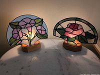 Both stained glass lamps illuminated on tabletop