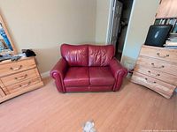 Front view of red leather loveseat showing full form, cushions, arms and back