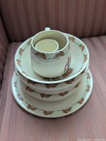 Stacked view of cup, egg cup, bowls and plate showing border pattern