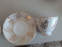 Top view of saucer and side of teacup showing gold foliage and dotted border