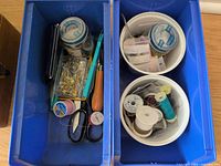 Blue trays holding thread spools, bobbins, pins, scissors and small tools