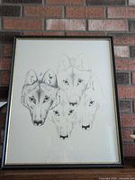 Full view of framed wolf print against brick background