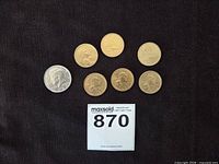 Group shot of six Sacagawea dollars and one Kennedy half dollar