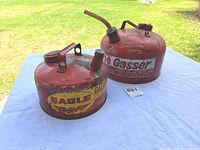 Both red metal gas cans on table outside
