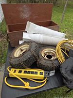 lot overview showing toolbox, downspout extensions, tires with chains, power bar, extension cord, mitts