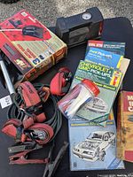 Automotive manuals, booster cables, tie-downs, boxed air pump, zip ties, portable heater visible