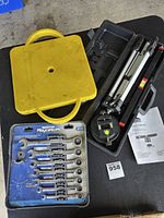 All items together: yellow scooter board, laser level kit in case, sealed wrench set