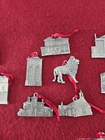Front views of multiple pewter ornaments with red ribbons