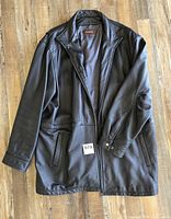 Front view of black leather coat showing overall design and exterior pockets