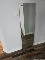 Full view of rectangular frameless mirror leaning against wall