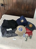 Overall lot: pants sealed, undershirts folded, four caps, three shot glasses