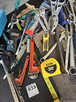 Wide view showing majority of tools including tape measure, pipe wrenches, ratchet packaging, corded tool, and wrenches