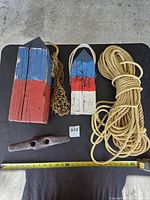 Full lot overview with two buoys, rope coil, net section, cleat and tape measure for scale