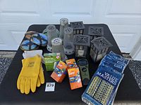 All items arranged on table: Thermacell device, refills, trimmer line spools, lanterns, candle holders, gloves