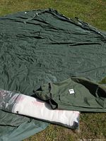 Green canopy fabric, carry bag and wrapped screen laid out on grass